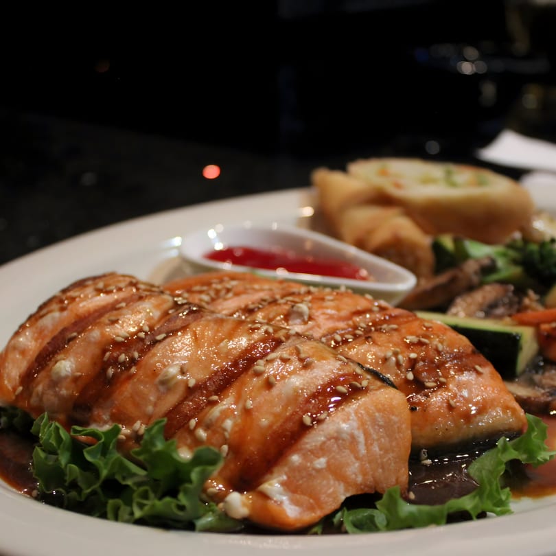 Uni Sushi's grilled salmon with sesame seeds, teriyaki sauce, lettuce, and a side of vegetables.